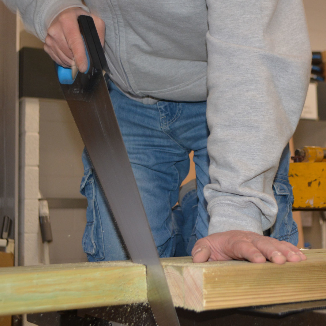 Workshop-1_ScaledToSize Man sawing a plank of wood in workshop